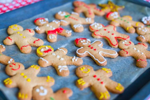 Raw gingerbread men with glaze on a baking sheet