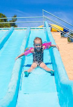 Child on water slide at aquapark during summer holiday