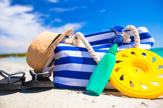 Stripe bag, straw hat, sunblock and towel on beach