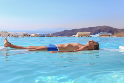 Young man in infinity swimming pool in Santorini, Greece