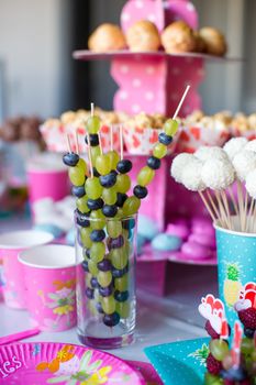 Canape of fruit, white chocolate cake pops and popcorn on sweet children's table at birthday party