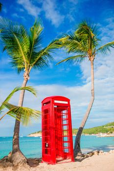 Beautiful landscape with a classic phone booth on the white sandy beach in Antigua