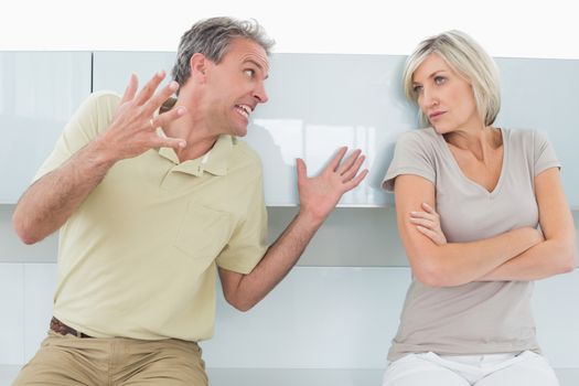 Woman with arms crossed as man argue in kitchen