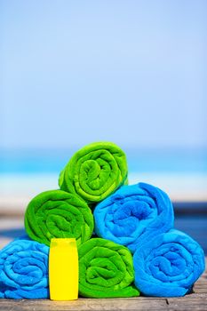 Close up of colorful towels and sunscreen bottle background the sea