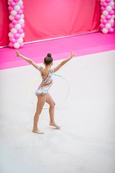 Beautiful little gymnast girl with rope on the carpet on the competition