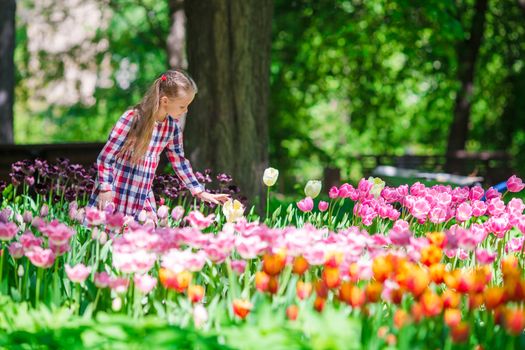 Little adorable girl in the lush garden of tulips
