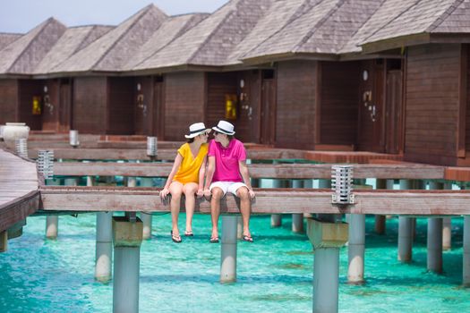 Young couple on beach jetty near water villa in honeymoon