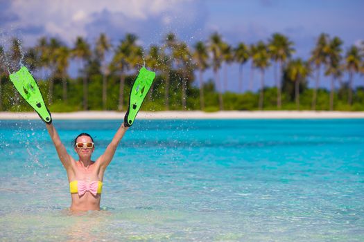 Travel beach fun concept - woman holding snorkeling fins standing in turquiose water