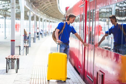 Young man with baggage at a train station near express train