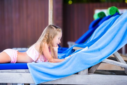 Little adorable girl on beach lounger near the swimming pool
