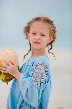 Little adorable girl drinking coconut milk on the beach