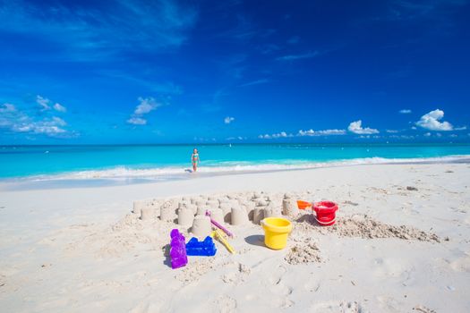 Sandcastle at white beach with plastic kids toys