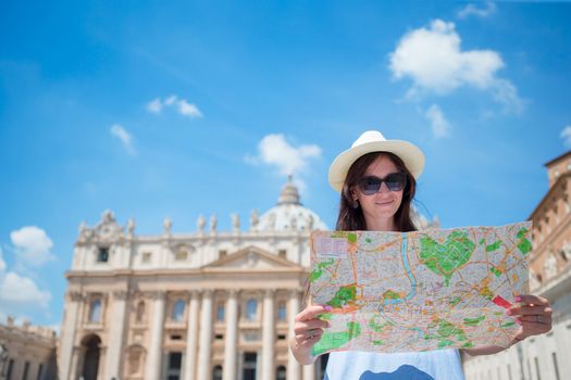 Happy young woman with city map in Vatican city and St. Peter's Basilica church, Rome, Italy. Travel tourist woman with map outdoors during holidays in Europe.