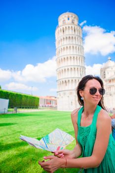 Young happy girl with toristic map on travel to Pisa. Tourist traveling visiting The Leaning Tower of Pisa.