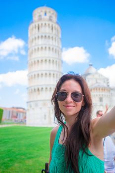 Tourist woman taking selfie background famous Pisa Tower. Woman traveling visiting The Leaning Tower of Pisa.