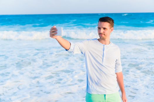 Young man taking selfie on the beach on caribbean vacation
