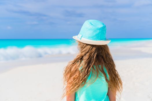 Little girl in hat walking at beach during caribbean vacation