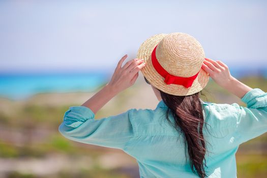 Young woman in hat on a tropical beach looking on the beautiful sea