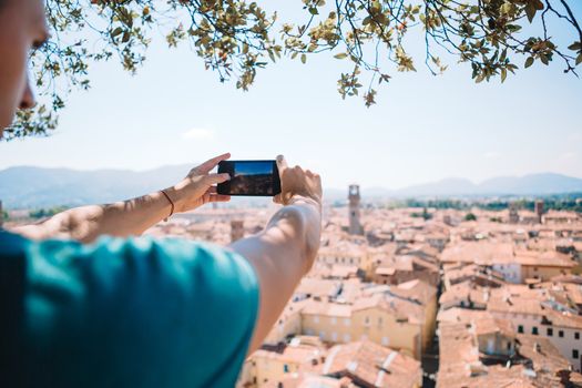 Young caucasian man making photo of european old city by mobile phone from the observation place