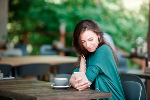 Young woman with smart phone while sitting alone in coffee shop during free time