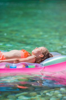 Adorable girl on inflatable air mattress in the sea