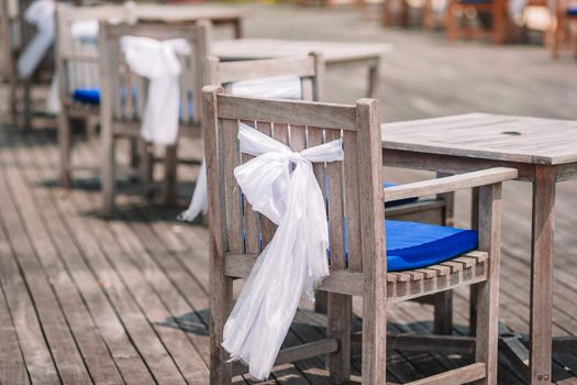 Wedding chairs decorated with white bows at outdoor cafe