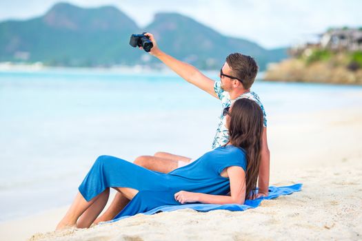 Happy couple taking a photo on white beach on honeymoon holiday