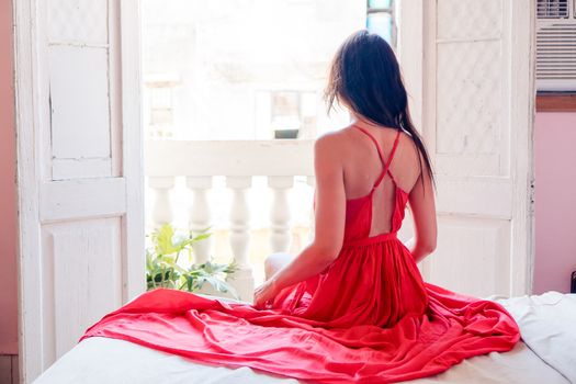 Young attractive woman in red dress in apartment in Havana
