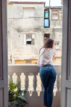 Young attractive woman on old balcony in apartments in Havana