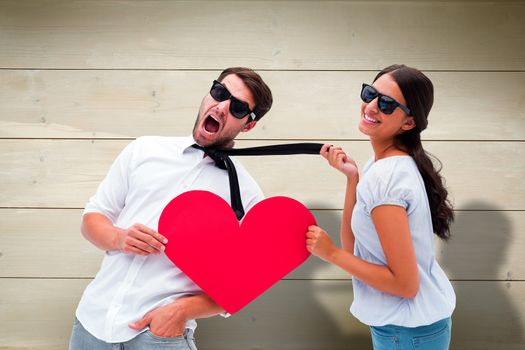 Composite image of brunette pulling her boyfriend by the tie holding heart