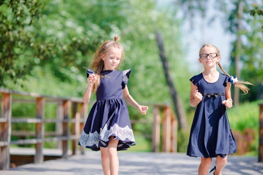 Adorable little school girls outdoors in warm september day. Back to school.
