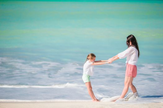 Beautiful mother and daughter at Caribbean beach enjoying summer vacation. Family walking on tropical famous Jolly bay beach