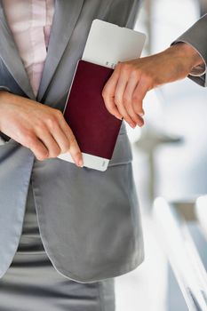 Portrait of young attractive businesswoman holding her passport and boarding pass in airport