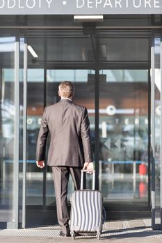 Businessman walking with his luggage in departure area at airport