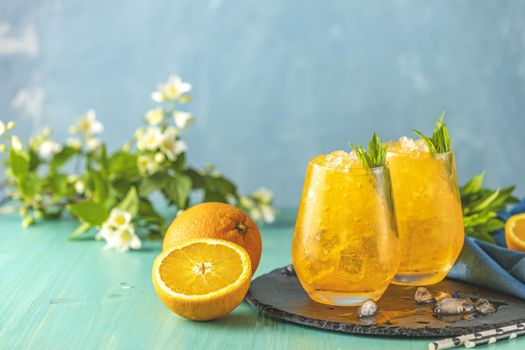 Two glass of orange ice drink with fresh mint on wooden turquois