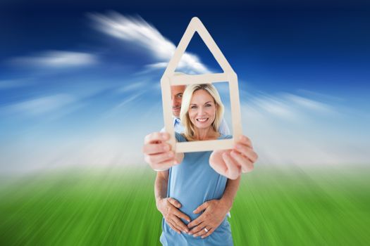 Composite image of happy couple holding house outline 