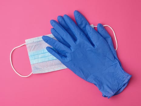 disposable gloves and medical mask made of non-woven material with white rubber bands on a pink background, protective accessory for the respiratory tract from the virus