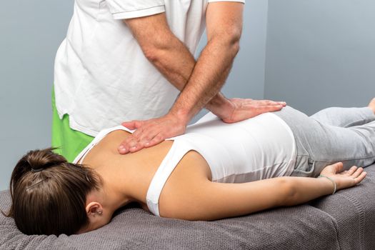 Physiotherapist applying pressure on female spine.