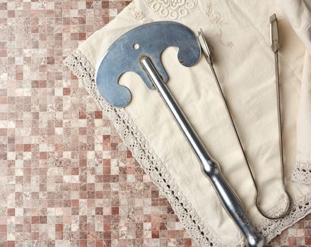 vintage iron knife and tongs on a beige kitchen towel