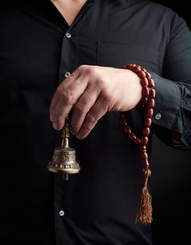 adult man in a black shirt holds a copper Tibetan ritual bell
