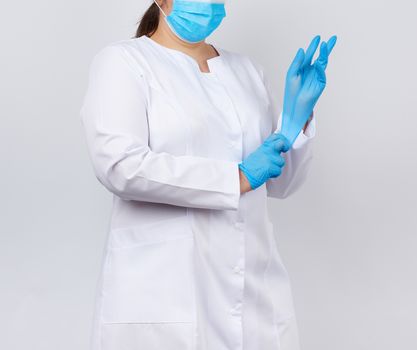 medical doctor in a white coat and mask puts on medical hands la