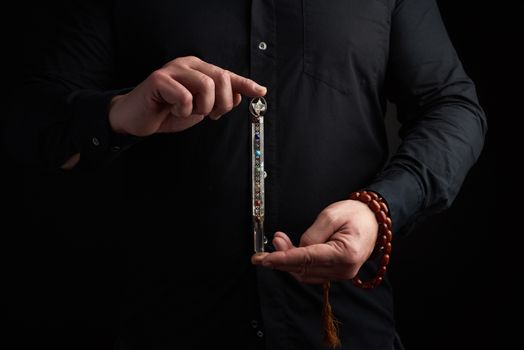 adult man in a black shirt holds a crystal chakra rod inlaid wit