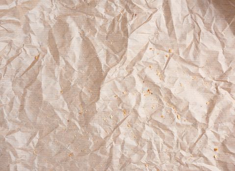 crumpled brown parchment paper with bread crumbs