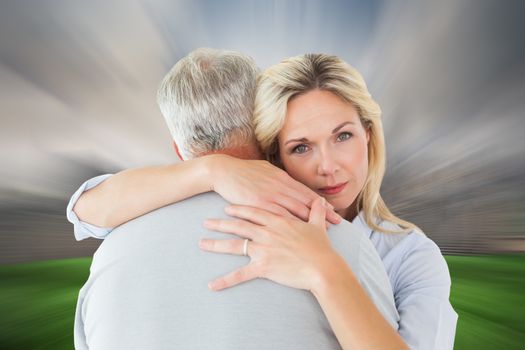 Composite image of unhappy blonde hugging her husband