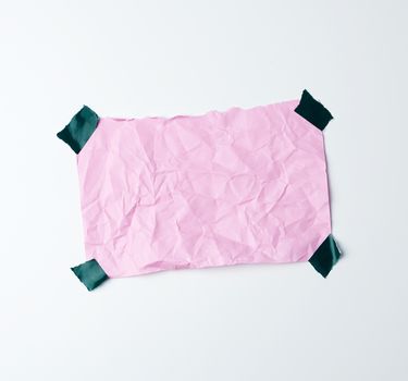 pink crumpled sheet of paper glued with adhesive tape on a white