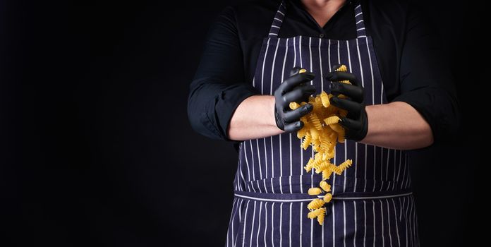 male cook in a striped apron and black latex gloves throws raw f