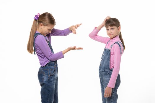 A girl shows a virtual object on her hand, another girl scratches her head in bewilderment