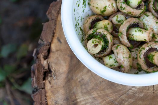 in a bowl raw mushrooms champignons in a marinade with herbs, dill in a rustic natural form. View from above