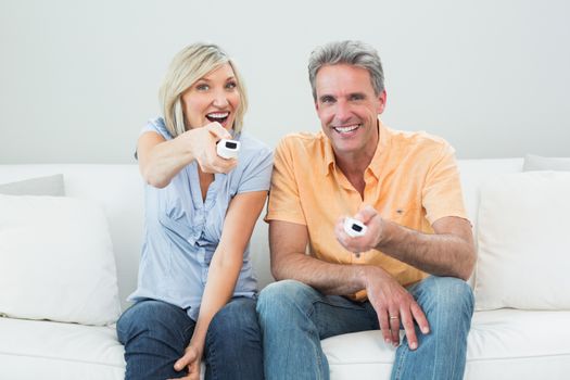 Cheerful couple with remote controls in a house