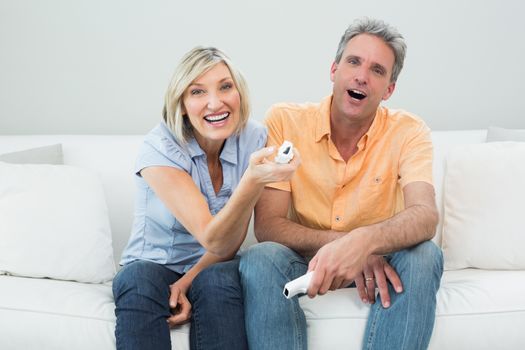 Portrait of a cheerful couple with remote controls